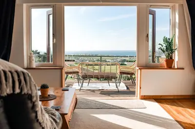a living room with a view of the ocean at Spacious Sea-View Apt. Overlooking St Ives Bay in Gwithian