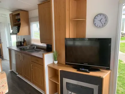 a kitchen with a television and a clock on the wall at Cornish coastal retreats- 74 newquay view in Porth