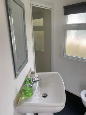 a bathroom with a white sink and a mirror at Cornish coastal retreats- 74 newquay view in Porth