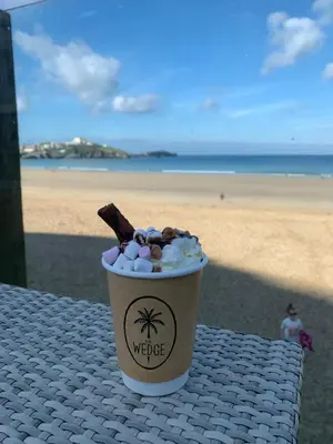 a cup of coffee sitting on a table next to the beach at Cornish coastal retreats- 74 newquay view in Porth
