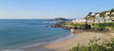 a beach with houses on a hill next to the ocean at Beautiful 3 bedroom cottage in the heart of Looe in Looe