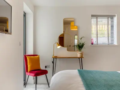 a bedroom with a red chair and a mirror at Chi An Mor in Charlestown