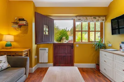 a living room with a couch and a window at Romantic, secluded cottage in Cardinham Woods, Cornwall in Cardinham