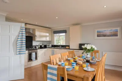 a kitchen with a wooden table with chairs and a dining room at Trevone House with Hot Tub on Retallack Resort in Padstow