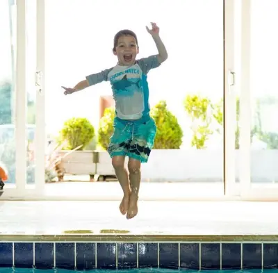 a young boy jumping into a swimming pool at Trevone House with Hot Tub on Retallack Resort in Padstow
