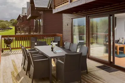 a patio with a table and chairs on a deck at Trevone House with Hot Tub on Retallack Resort in Padstow