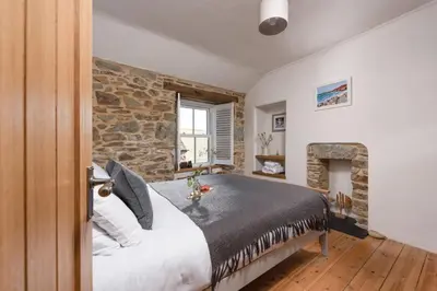 a bedroom with a large bed and a stone wall at 2 Bedroom Home in Marazion, views of St Michael's Mount in Marazion