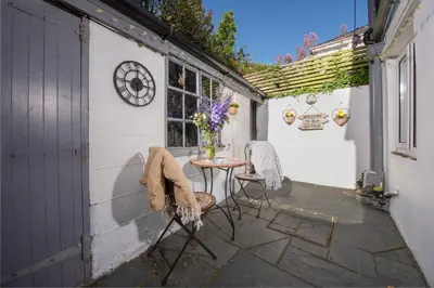 a patio with a table and chairs and a window at 2 Bedroom Home in Marazion, views of St Michael's Mount in Marazion