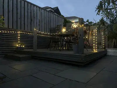 a patio with string lights on a fence at 2 Bedroom Home in Marazion, views of St Michael's Mount in Marazion