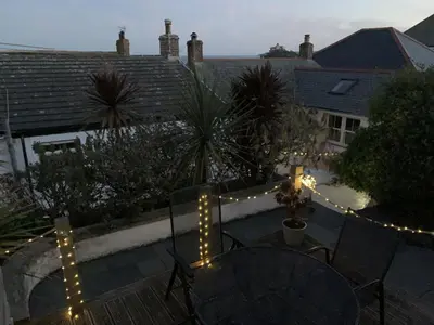 a patio with string lights and a table and chairs at 2 Bedroom Home in Marazion, views of St Michael's Mount in Marazion
