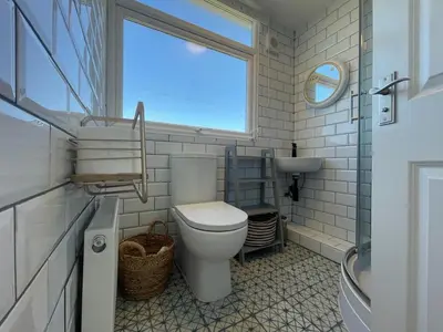 a bathroom with a toilet and a window and a sink at Baywatch Mawgan Porth Spacious Home sleeps 9, Games room, Parking & Garden in Mawgan Porth
