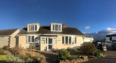 a white house with a black roof at Baywatch Mawgan Porth Spacious Home sleeps 9, Games room, Parking & Garden in Mawgan Porth