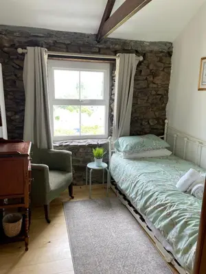 a bedroom with a bed and a chair and a window at Buttercup Cottage, located in the gateway to Eden! in Saint Blazey