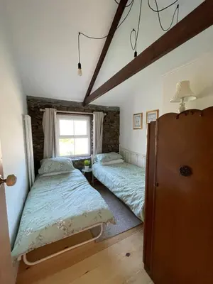 a bedroom with two beds and a window at Buttercup Cottage, located in the gateway to Eden! in Saint Blazey
