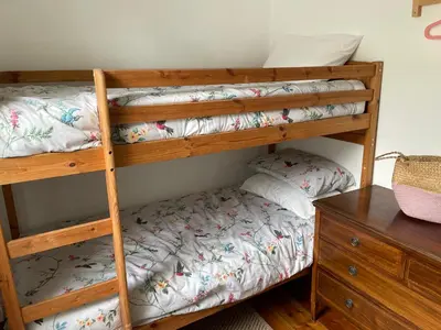 a bedroom with two bunk beds and a desk at Buttercup Cottage, located in the gateway to Eden! in Saint Blazey