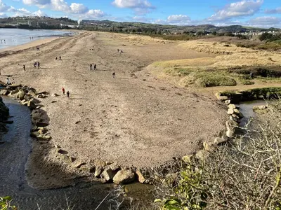 a group of people walking on the beach at Buttercup Cottage, located in the gateway to Eden! in Saint Blazey