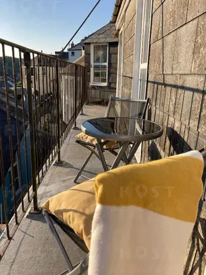 a patio with a table and chairs on a balcony at Looe with a View - Entire apartment with FREE allocated parking in Looe
