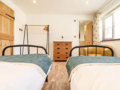a bedroom with two beds and a dresser at Polurrian House in Helston