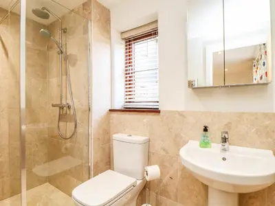 a bathroom with a shower and a toilet and a sink at Polurrian House in Helston