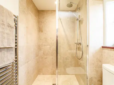 a shower with a glass door in a bathroom at Polurrian House in Helston