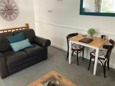a living room with a couch and a table and a clock at The Granary at Bissick Old Mill in Truro