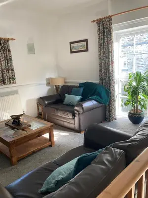 a living room with a leather couch and a coffee table at The Granary at Bissick Old Mill in Truro