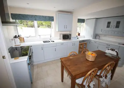 a kitchen with white cabinets and a wooden table at Detached House 2 Bed Sleeps 4 Parking in Fowey
