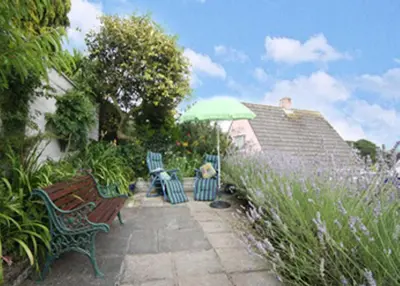 a patio with two benches and an umbrella at Detached House 2 Bed Sleeps 4 Parking in Fowey