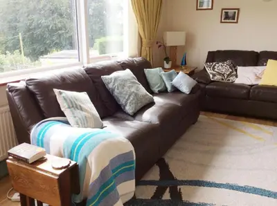a brown leather couch in a living room with a window at Detached House 2 Bed Sleeps 4 Parking in Fowey