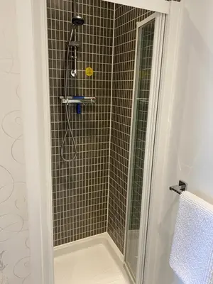 a shower stall with a glass door with a shower at Stylish 3 bed home with allocated parking for 2 in Liskeard