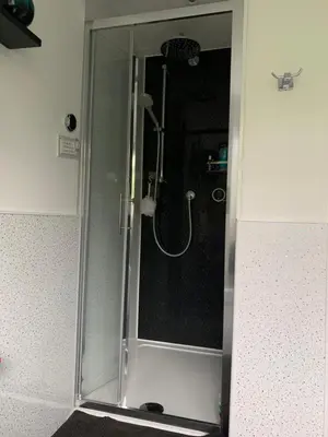 a shower with a glass door in a bathroom at West Winds, Fore Street, Polruan by Fowey in Polruan