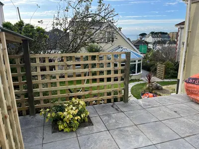 a wooden fence with flowers on a patio at West Winds, Fore Street, Polruan by Fowey in Polruan