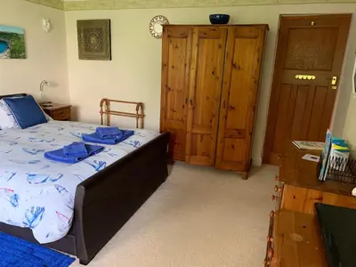 a bedroom with a bed and a wooden closet at West Winds, Fore Street, Polruan by Fowey in Polruan