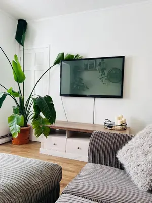 a living room with a couch and a tv on a wall at The Annexe at Tenniside in Perranporth