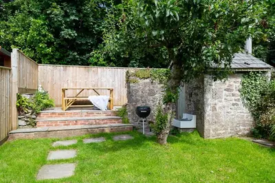 a backyard with a wooden fence and a grill at Charlestown cottage, Woodburner, Gardens & Parking in Charlestown