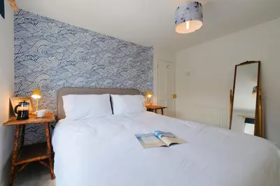 a bedroom with a white bed with a book on it at Finest Retreats - Primrose Cottage in Tywardreath
