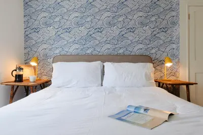 a book laying on top of a white bed at Finest Retreats - Primrose Cottage in Tywardreath