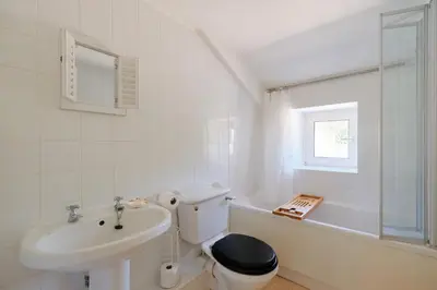 a white bathroom with a sink and a toilet and a tub at Finest Retreats - Primrose Cottage in Tywardreath