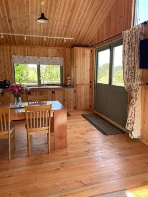 a room with a table and a kitchen with wooden floors at Rural Wood Cabin - less than 3 miles from St Ives in Penzance