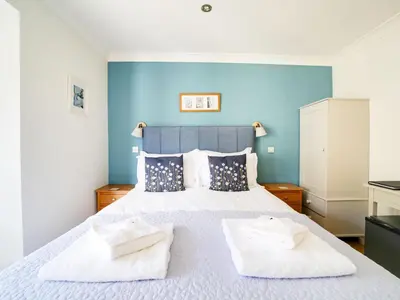a bedroom with a bed with two towels on it at The Artist Loft, Ensuite Guest Rooms, Porthleven in Porthleven