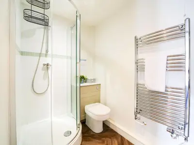 a bathroom with a toilet and a glass shower at The Artist Loft, Ensuite Guest Rooms, Porthleven in Porthleven