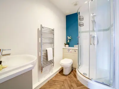 a white bathroom with a shower and a toilet at The Artist Loft, Ensuite Guest Rooms, Porthleven in Porthleven
