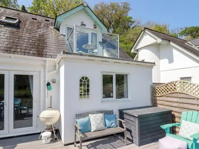 a white house with a deck with chairs at Penpoll in Wadebridge