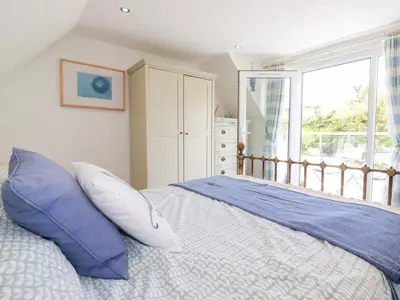 a bedroom with a bed with blue pillows and a window at Penpoll in Wadebridge
