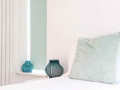 a pillow and a vase sitting on a bed at Penpoll in Wadebridge