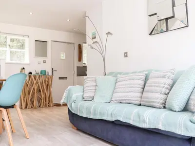 a living room with a blue couch and a kitchen at Penpoll in Wadebridge