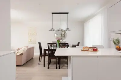 a white kitchen and dining room with a table and chairs at Tralee in Portreath