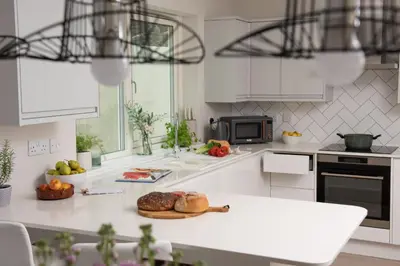 a kitchen with white cabinets and a plate of food on a counter at Tralee in Portreath