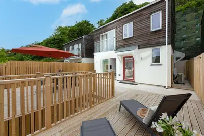 a deck with a wooden fence and a house at Tralee in Portreath