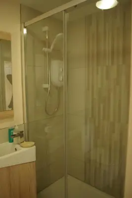 a shower with a glass door in a bathroom at Rural retreat, central location, close to beaches in Camborne